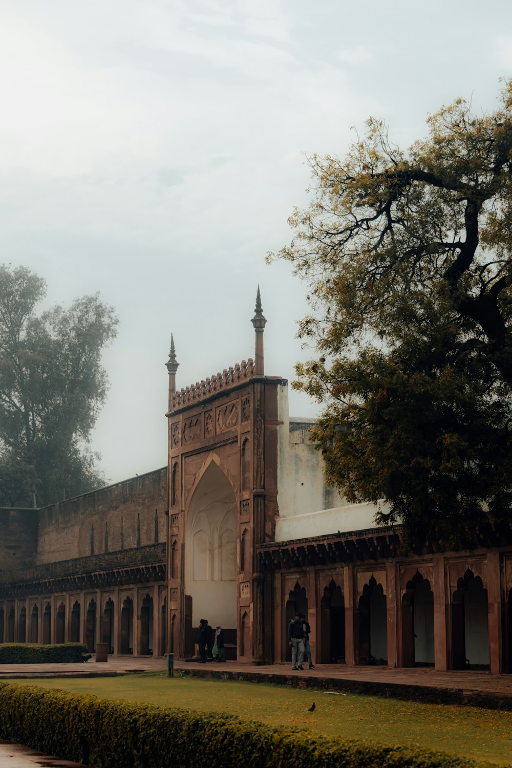 a large building with a tall tower next to a tree