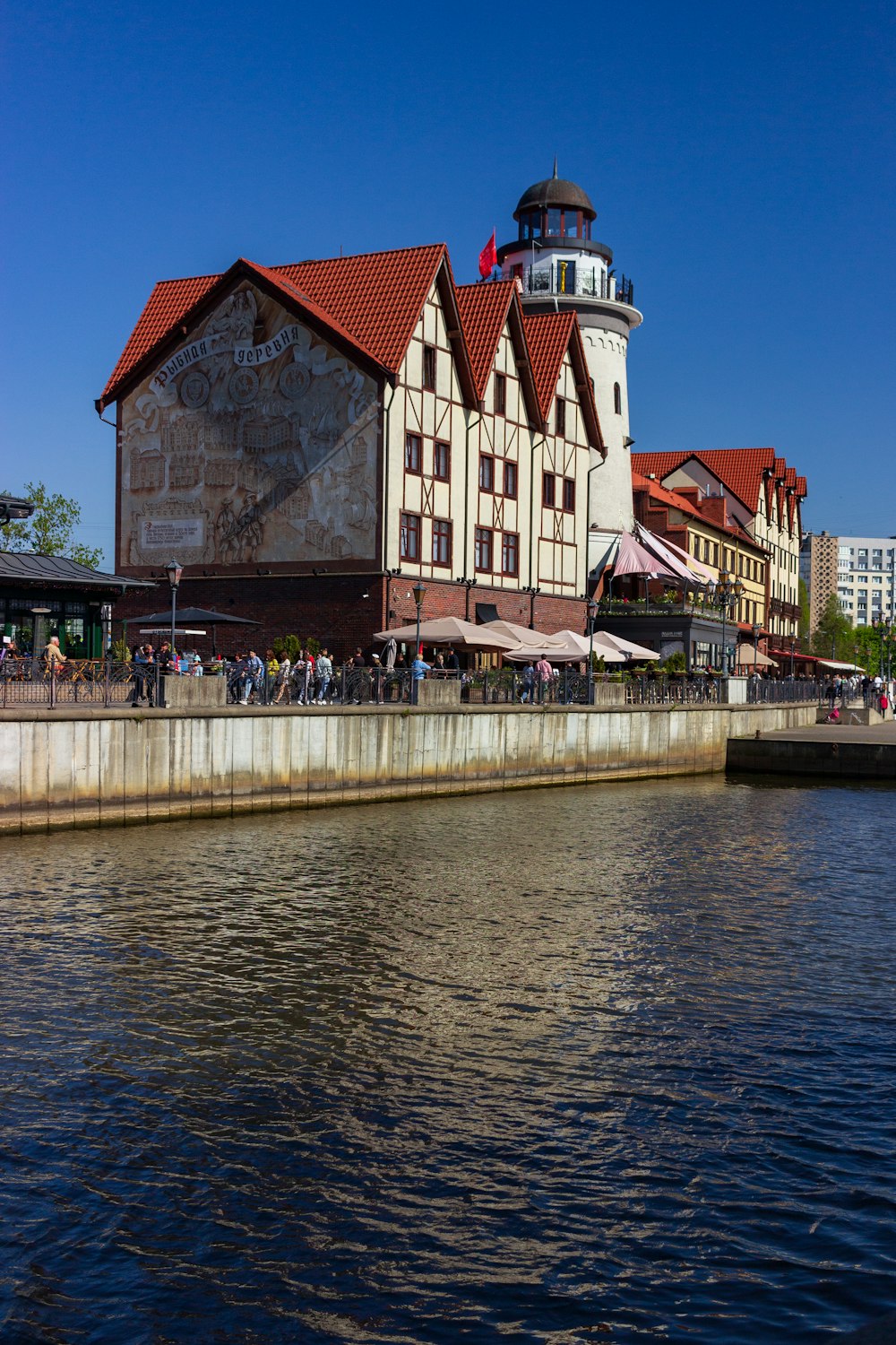 a building with a red roof next to a body of water