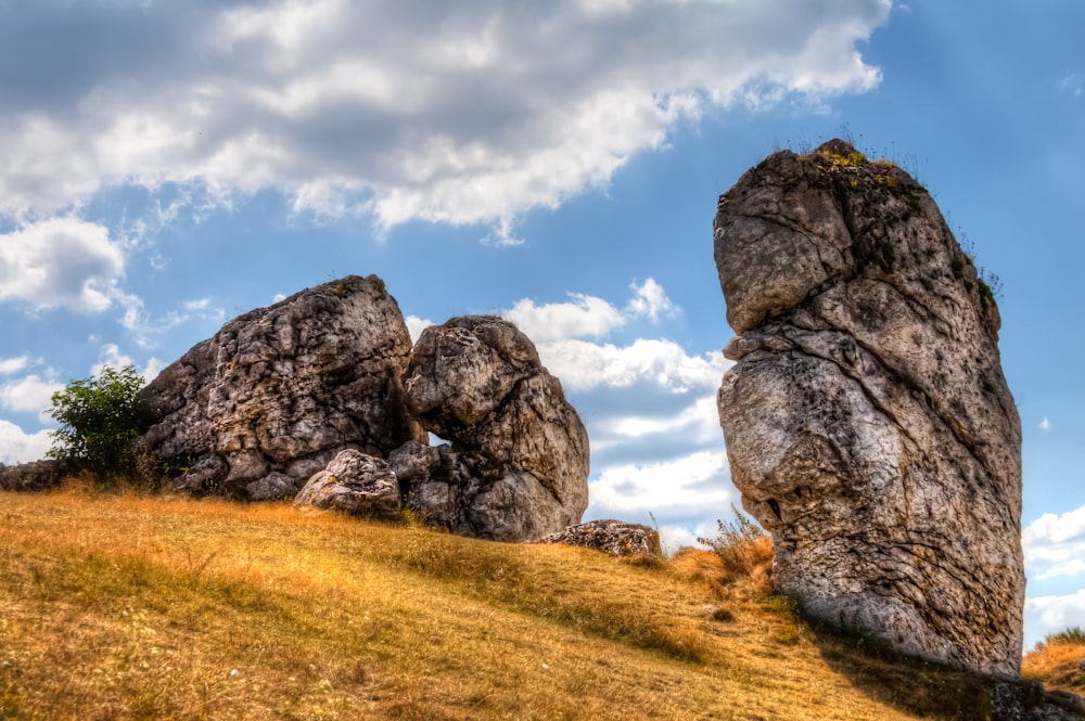 a large rock formation sitting on top of a grass covered hillside
