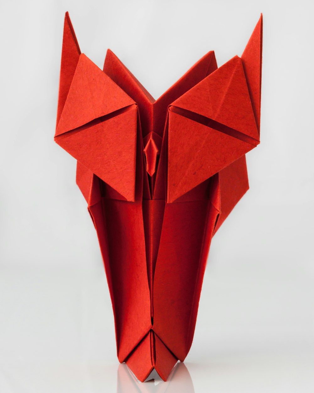 a red origami animal head on a white background