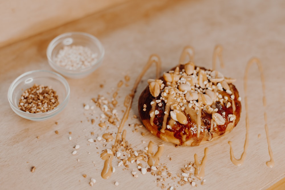 a donut covered in nuts sitting on top of a wooden table