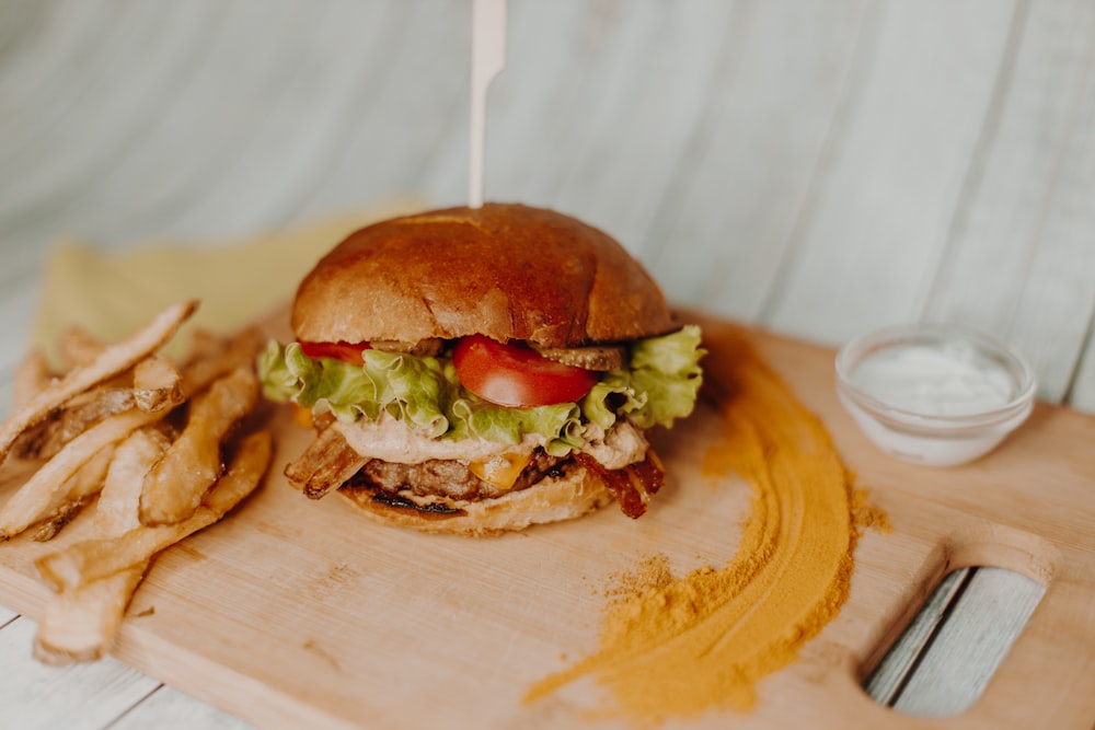 a close up of a sandwich on a cutting board with french fries