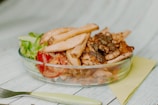 a glass bowl filled with meat and vegetables