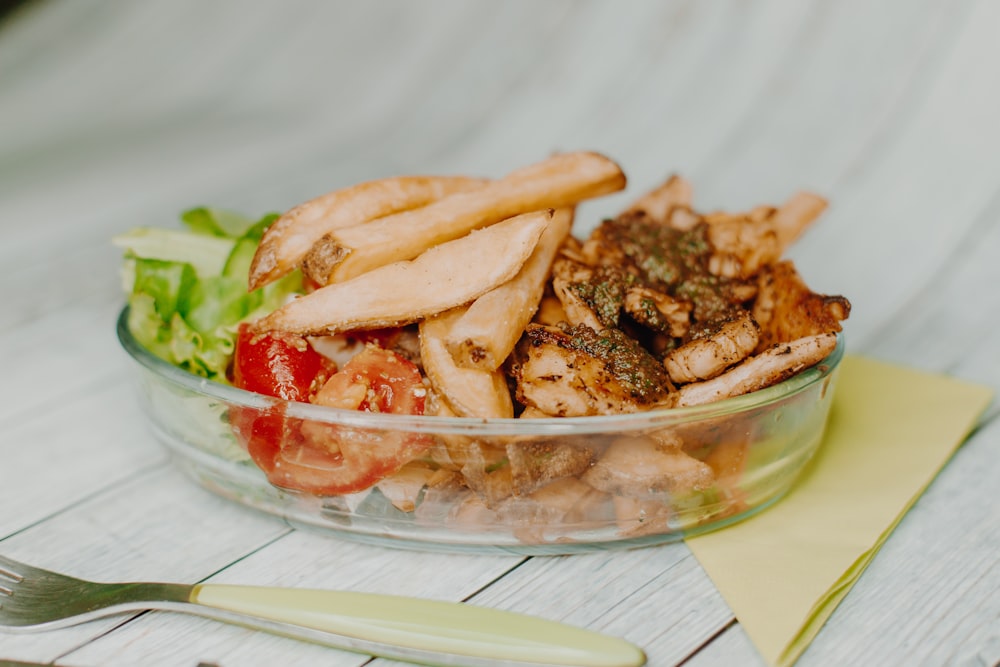 a glass bowl filled with meat and vegetables