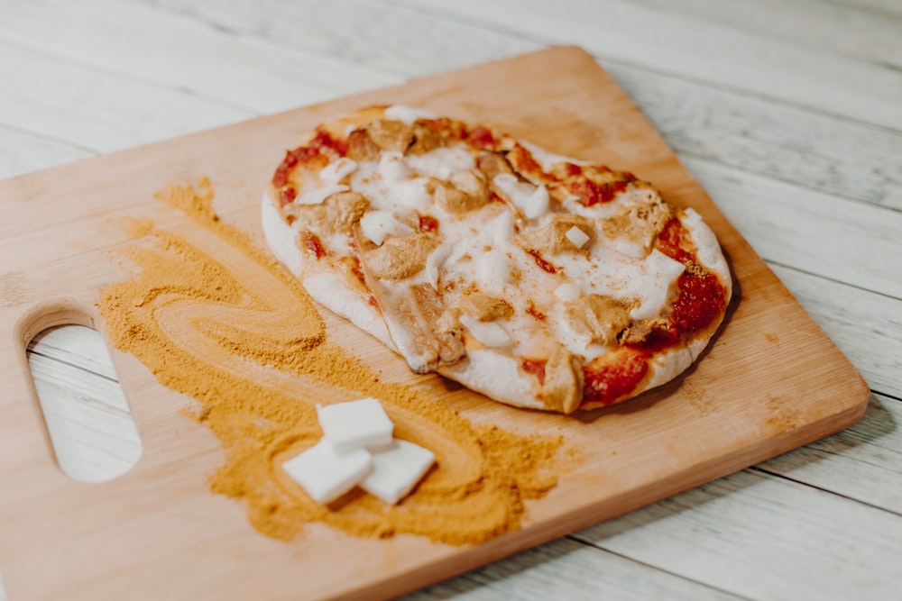 a pizza sitting on top of a wooden cutting board