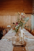 Rustic dinner table adorned with natural flower arrangements in pastel greens.