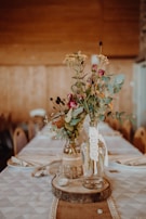 Close-up of a floral centerpiece blending wildflowers and greenery in a rustic vase.