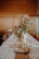 Elegant floral centerpiece featuring white lilies and eucalyptus on a rustic table.