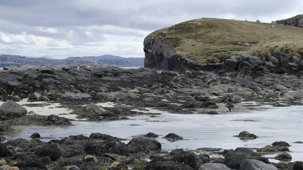 a rocky shore with a body of water in the foreground