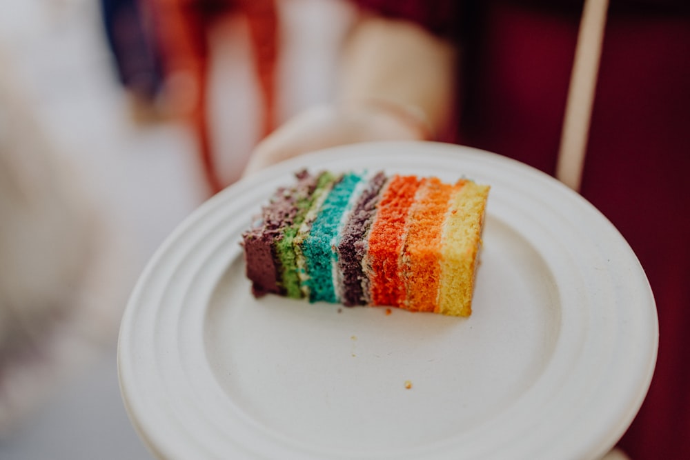 a person holding a plate with a piece of cake on it