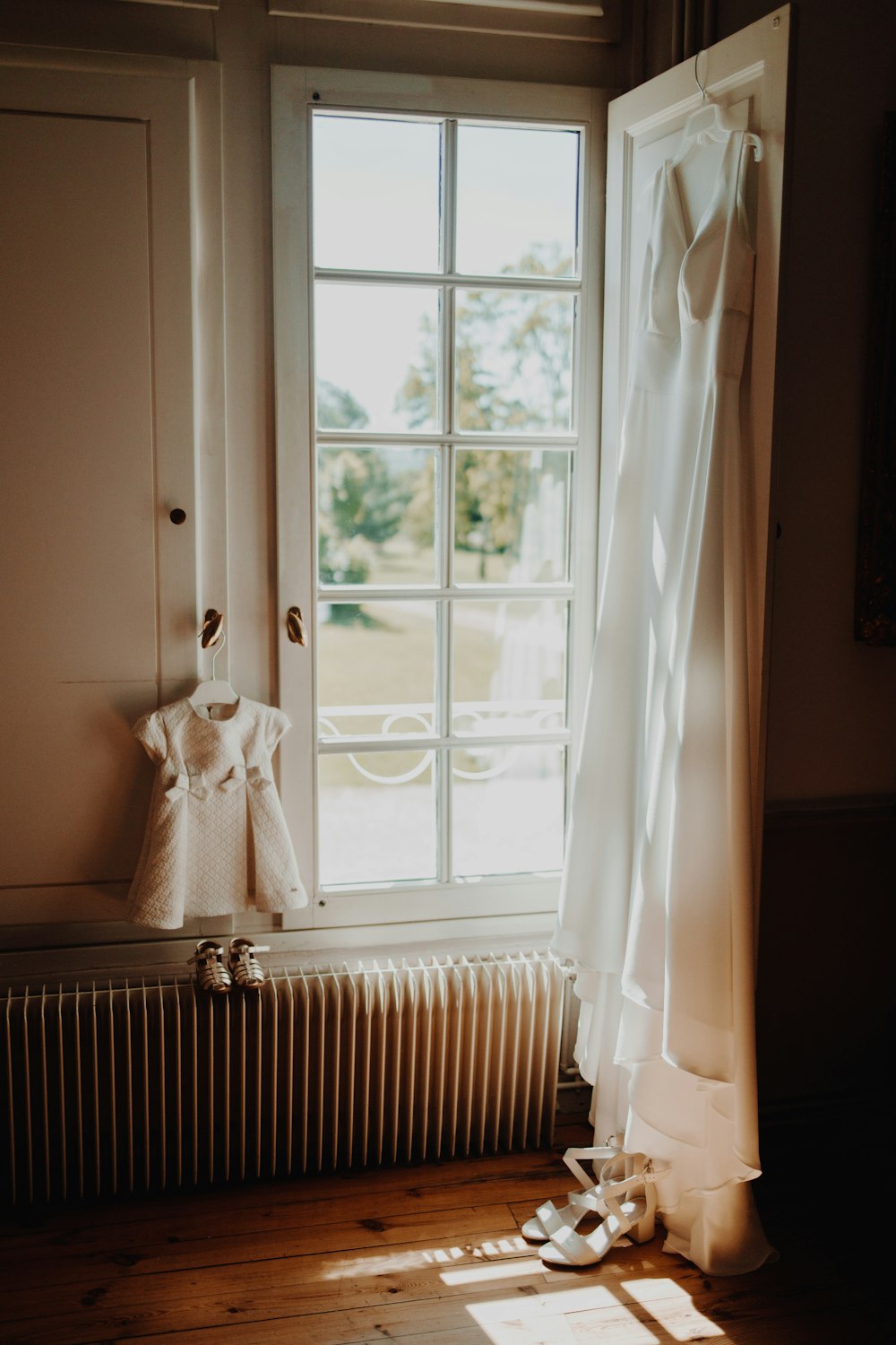 une robe blanche accrochée au rebord d’une fenêtre à côté d’un radiateur