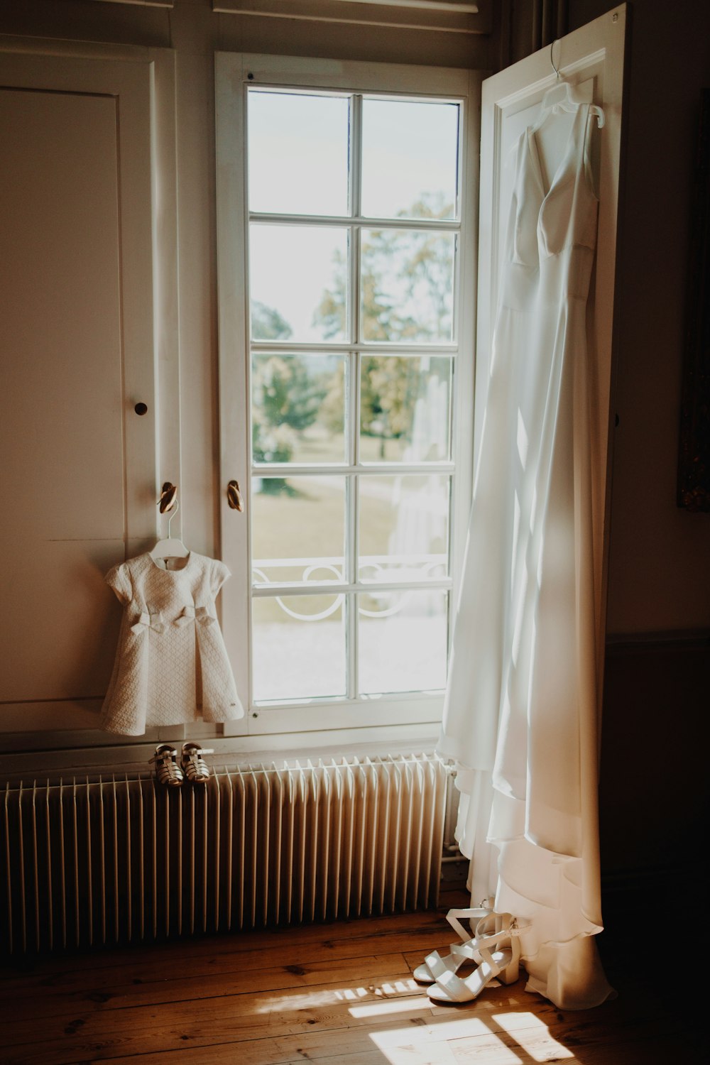 a white dress hanging on a window sill next to a radiator