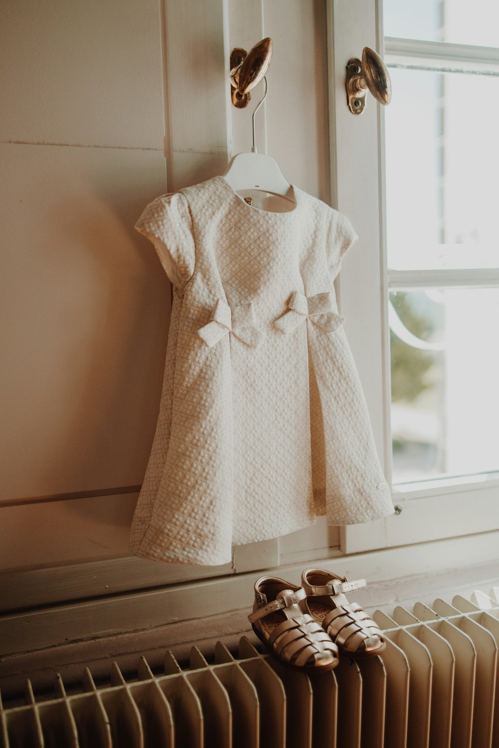 a white dress hanging on a radiator next to a pair of shoes