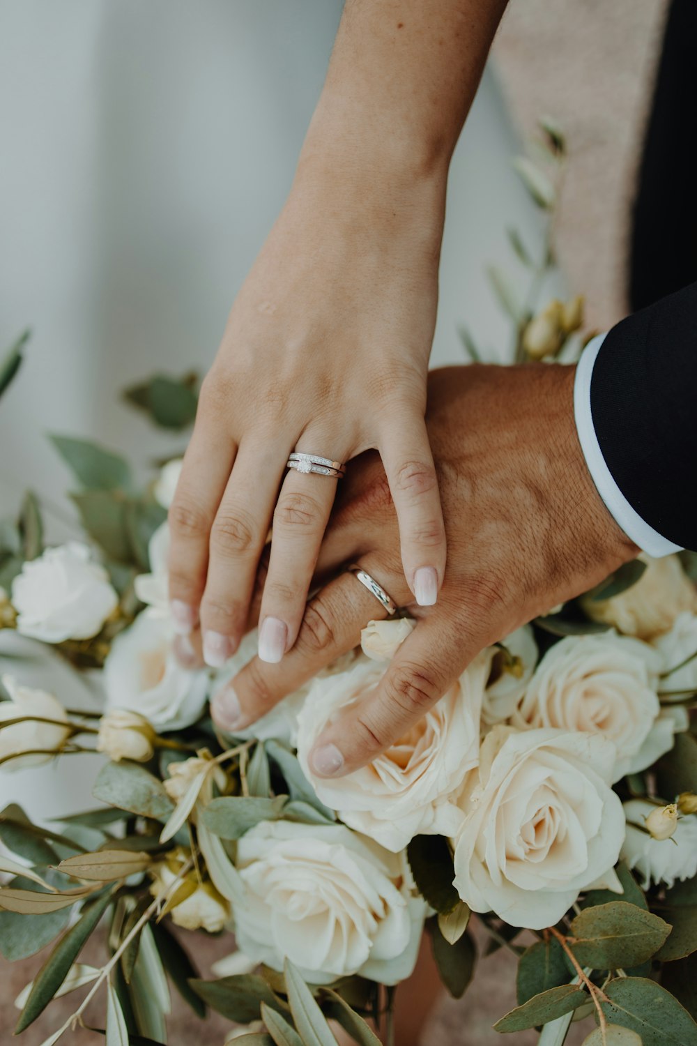 a close up of two people holding hands over a bouquet of flowers