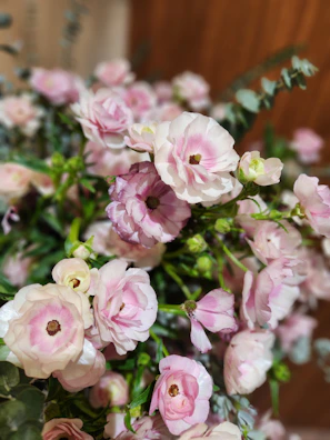 A delicate tribute arrangement with white lilies, soft pink roses, and ferns.