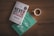 Two books are placed on a wooden surface beside a cup of coffee. One book has a white cover with the title 'Never Split the Difference' in bold red and black text. The other book has a turquoise cover with the title 'The Making of a Manager' in white text.
