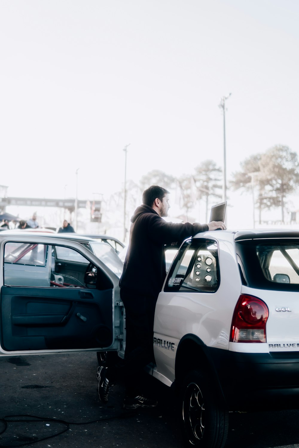 um homem ao lado de um carro branco em um estacionamento