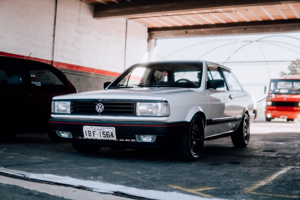 a white car parked in a garage next to another car