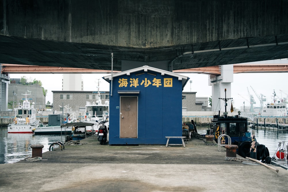 a small blue building sitting on top of a pier