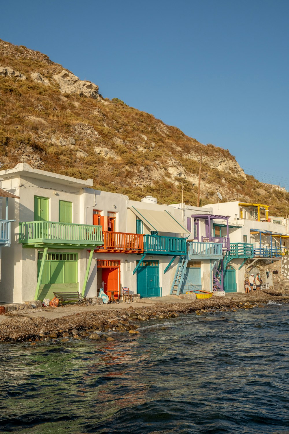 a row of multicolored buildings next to a body of water