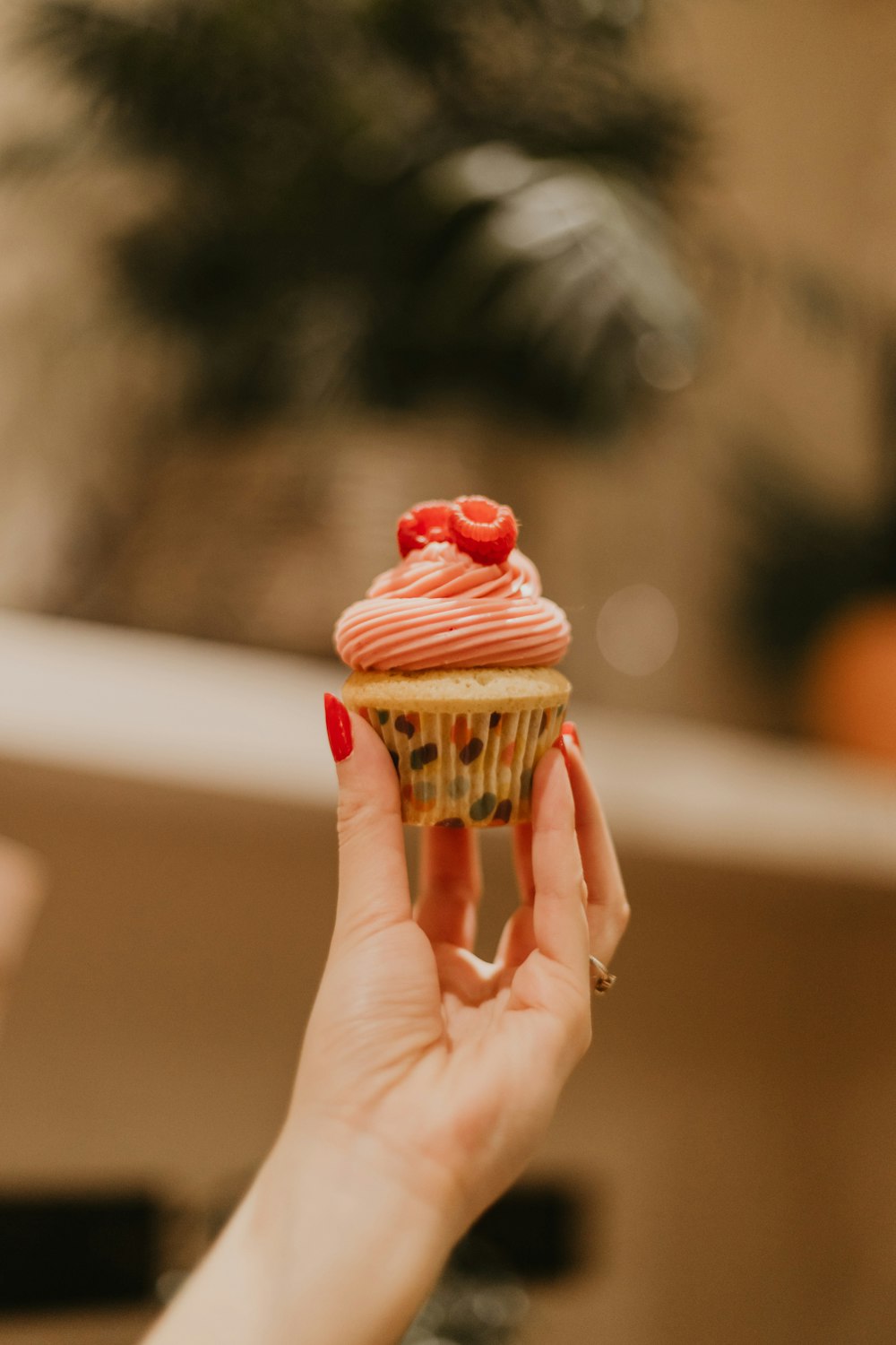 a woman holding a cupcake with pink frosting