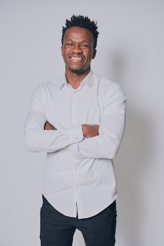 A smiling person wearing a soft, simple white tee standing against a plain background.