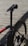 A close-up view of a bicycle focusing on the seat, seat post, and rear section of the frame and wheel. The bicycle has a sleek, modern design with a predominantly black frame and red accents. The background consists of wooden planks creating a rustic setting.