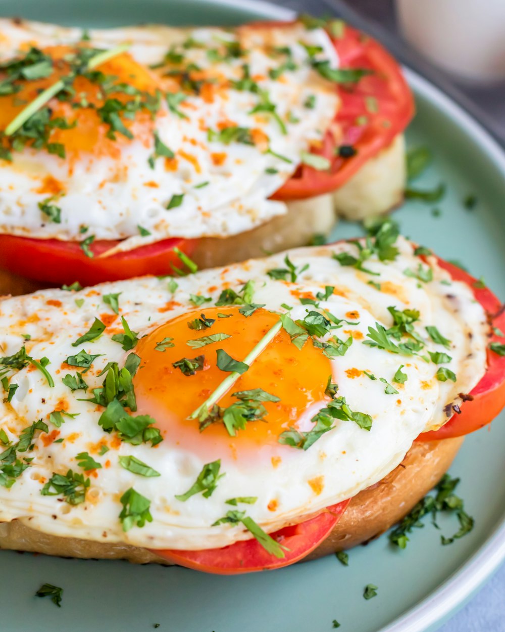 two pieces of toast topped with an egg and tomato