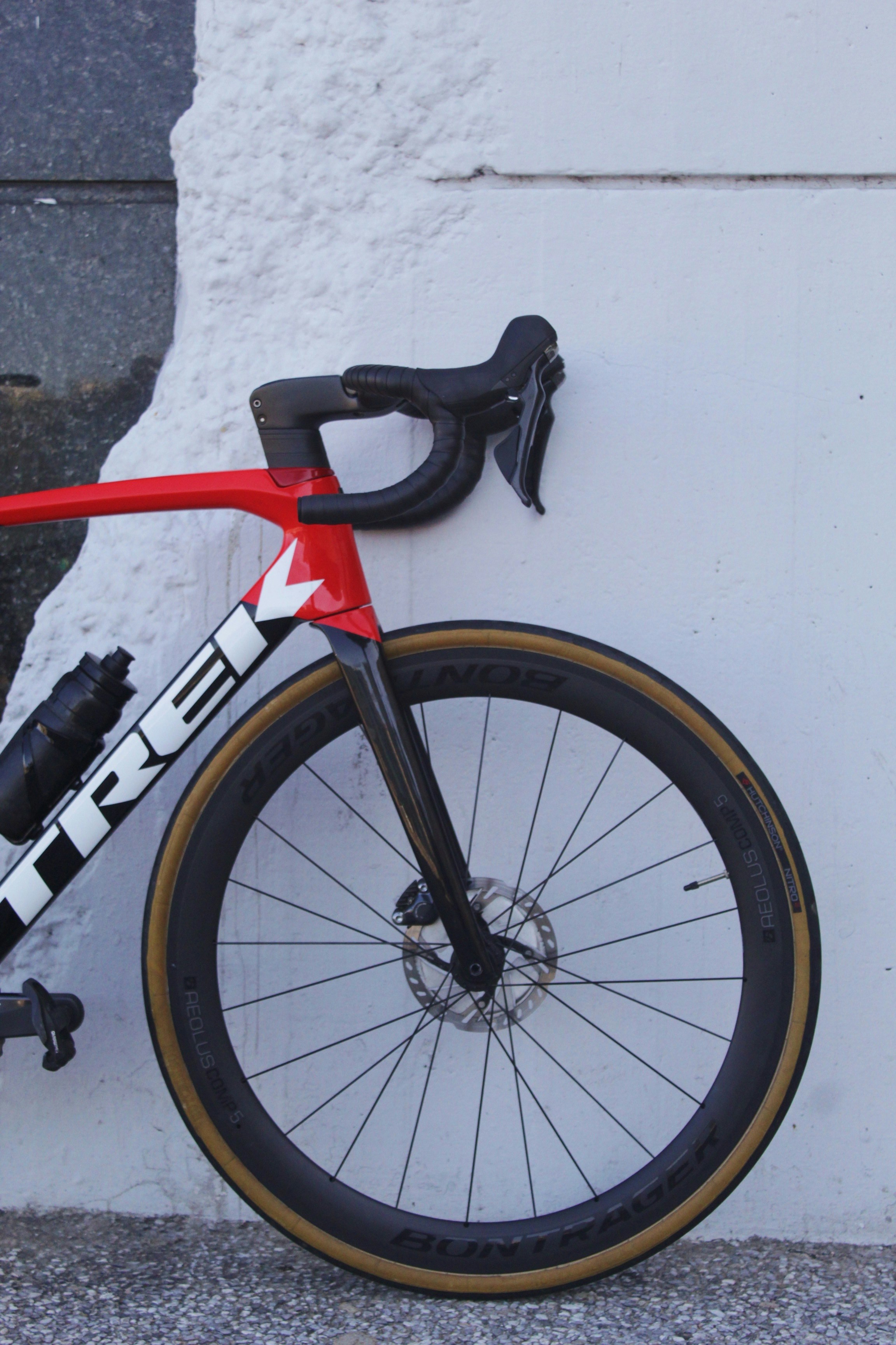 a red and black bike leaning against a white wall