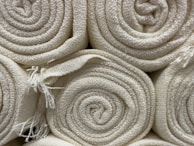 Smooth wool fabric rolls stacked neatly, highlighting their rich texture.