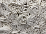 A collection of neatly rolled white towels stacked closely together in an orderly fashion.