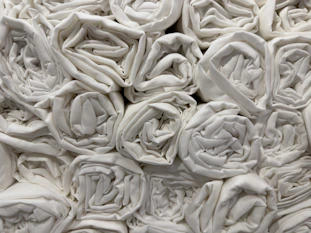 Stack of crisp white bed sheets and plush navy towels neatly arranged in a hotel room.