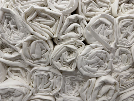 Freshly folded white linens and towels stacked neatly in a clean laundry room.
