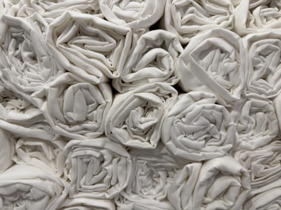 A collection of neatly rolled white towels stacked closely together in an orderly fashion.