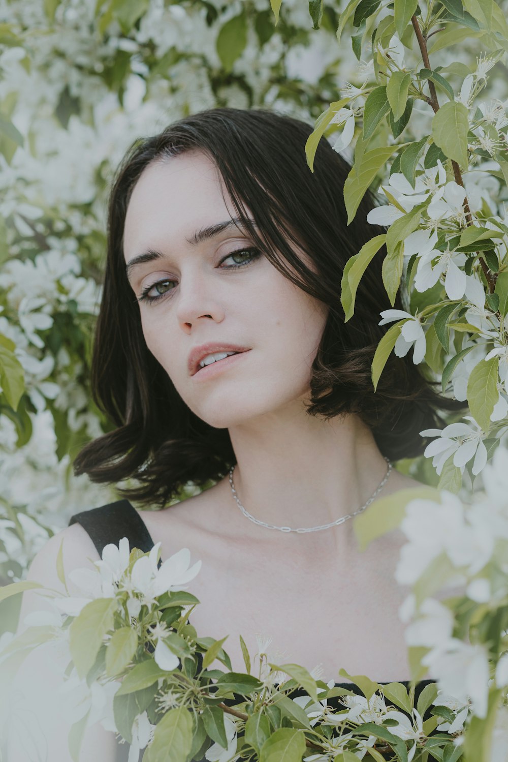 a woman standing in front of a tree with white flowers