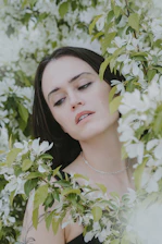 A calm woman practicing mindful meditation surrounded by soft greenery.