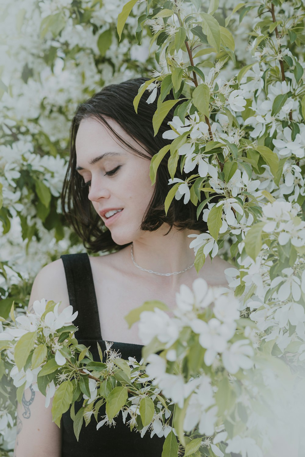 a woman standing in front of a tree with white flowers