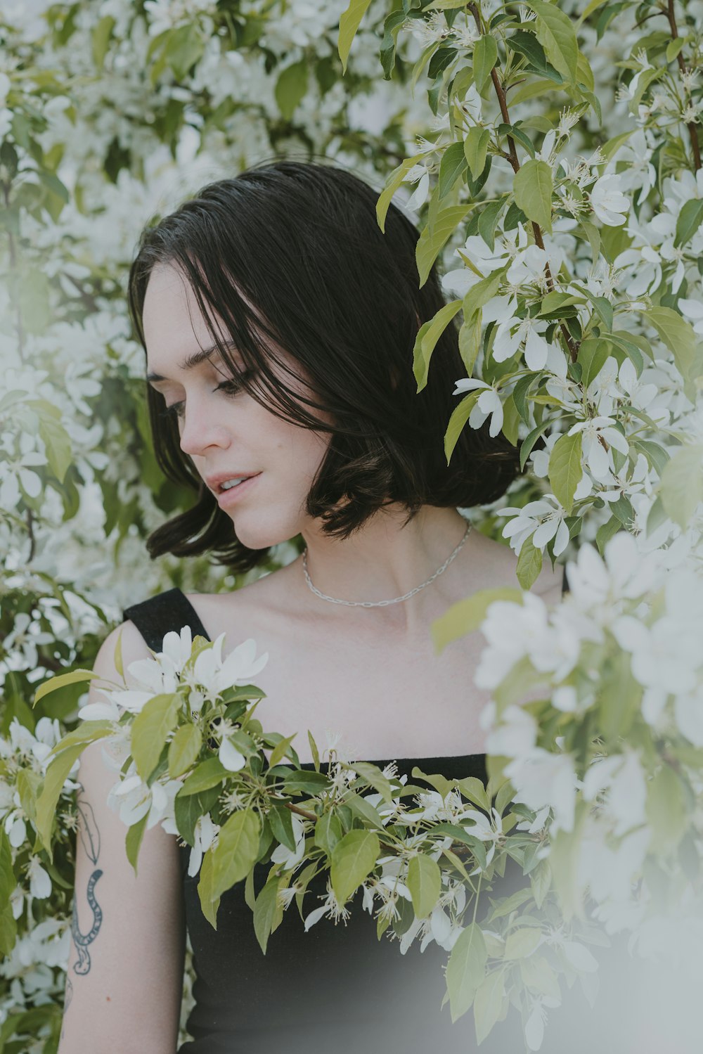 a woman standing in front of a tree with white flowers