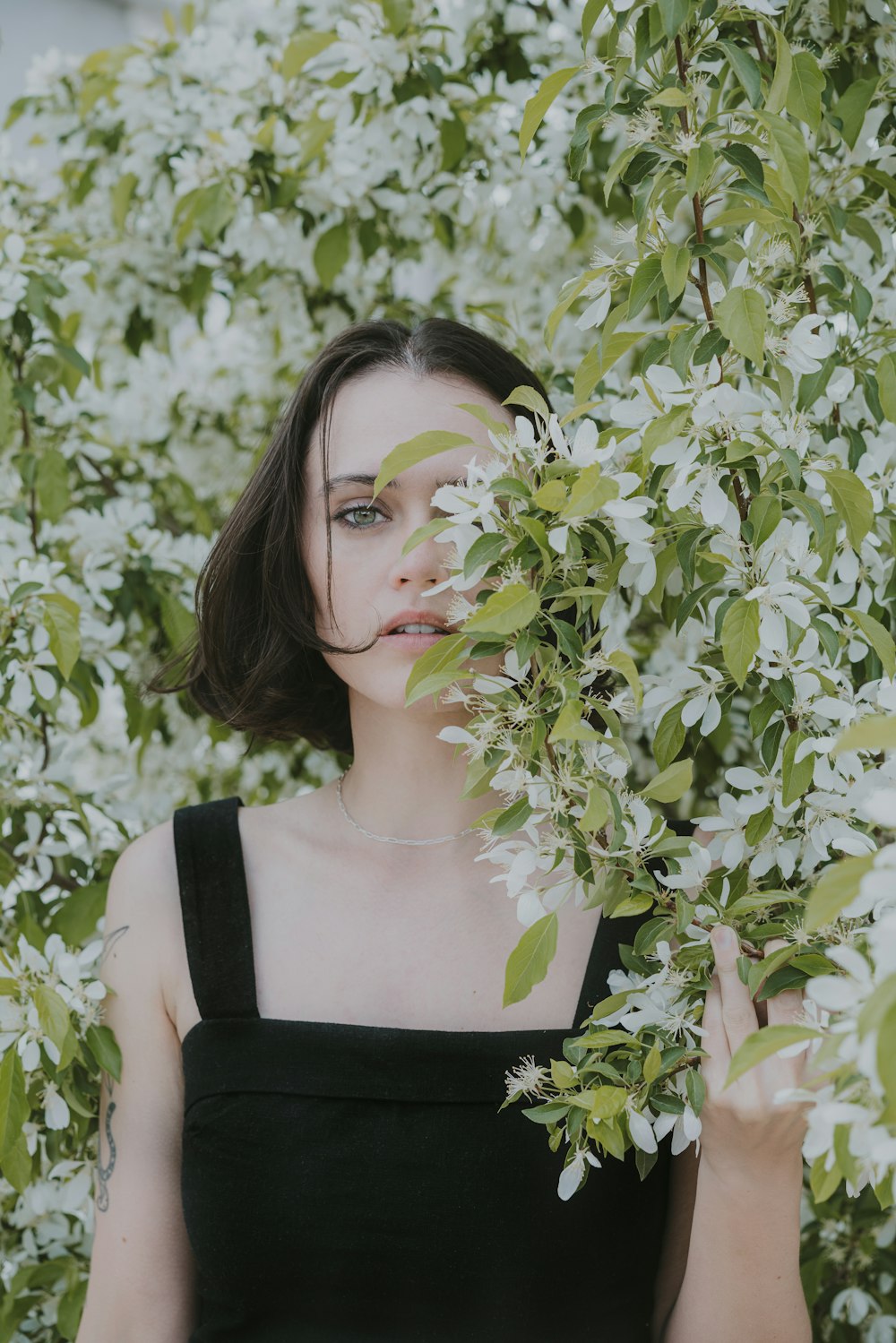 a woman standing in front of a tree with white flowers