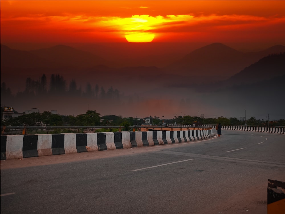 Una persona che guida una moto su una strada con un tramonto sullo sfondo