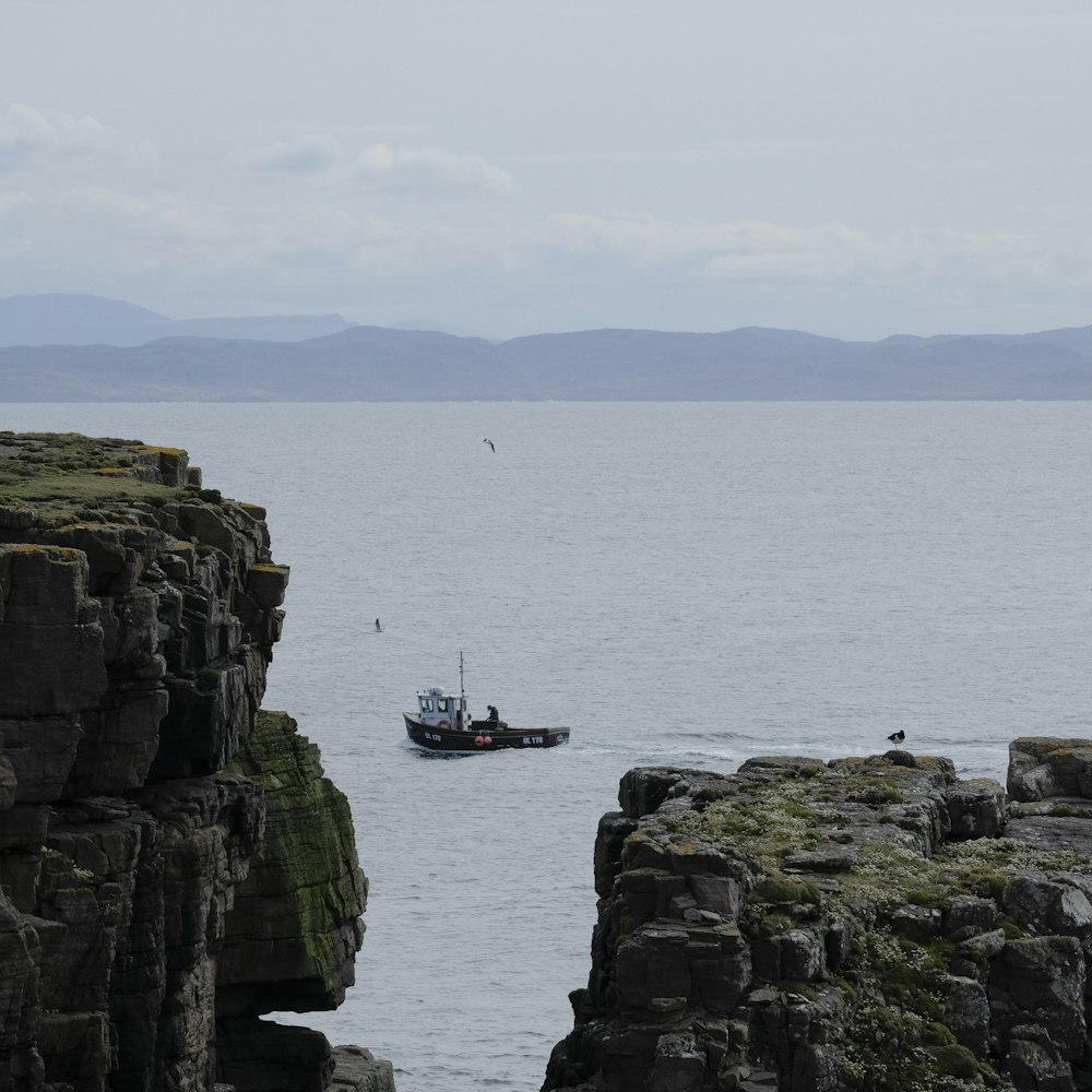 a boat is in the water near a rocky cliff