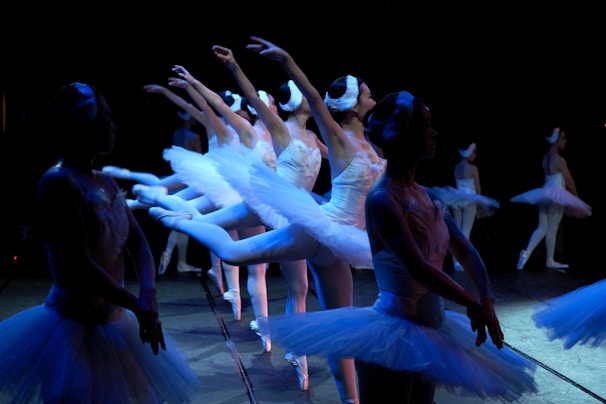 Children happily participating in a ballet class wearing blue and red outfits.