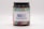 A brown jar with a black lid featuring a brightly colored label. The label displays the text 'NOBS' in large blue letters, along with the slogan 'Toothpaste without the BS.' The background of the label has a colorful, abstract pattern including shades of green, pink, and purple.