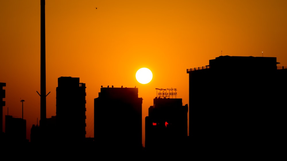 the sun is setting over a city with tall buildings