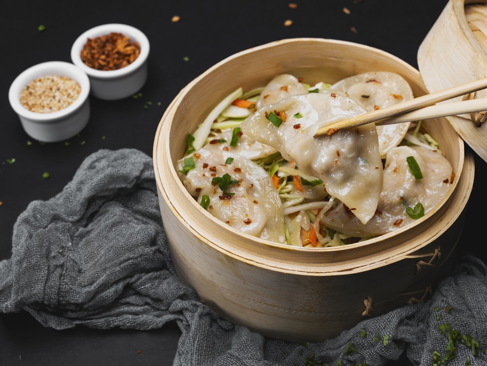 a wooden bowl filled with dumplings and vegetables