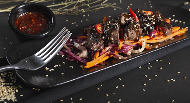 A colorful Don bento featuring grilled meat and vibrant side dishes in a black container.