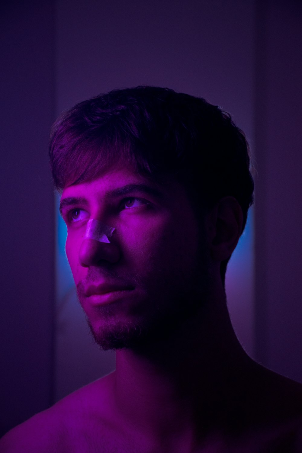 a man in a dark room with a purple light
