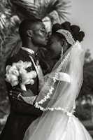 a bride and groom kissing in front of a palm tree