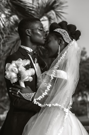 a bride and groom kissing in front of a palm tree