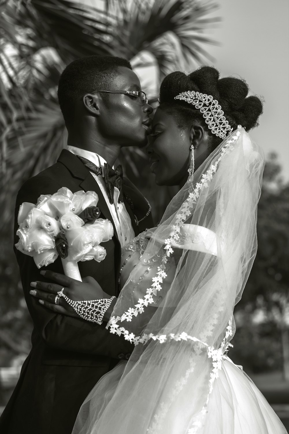 a bride and groom kissing in front of a palm tree